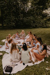 Group of women having a picnic in a park, enjoying food and leisure on a sunny day.